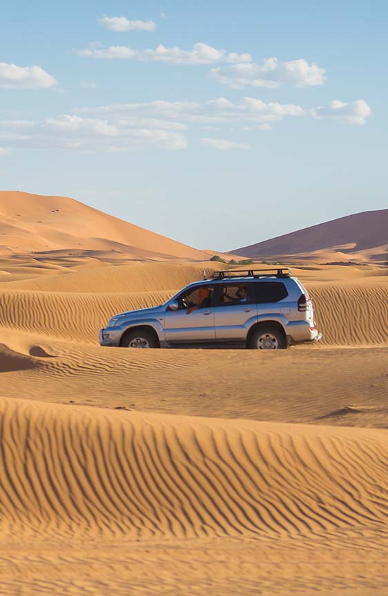 Car driving through desert sand.